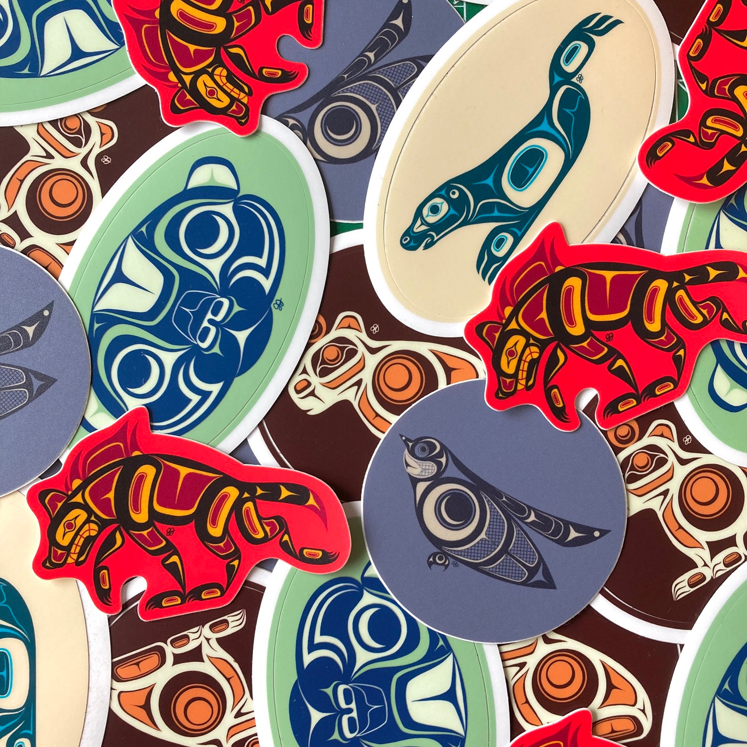 Assorted TeleKitnetic Art stickers layered together, showing stylized ravens, wolves, otters, bears, birds, and other animal designs in bold graphic colours.