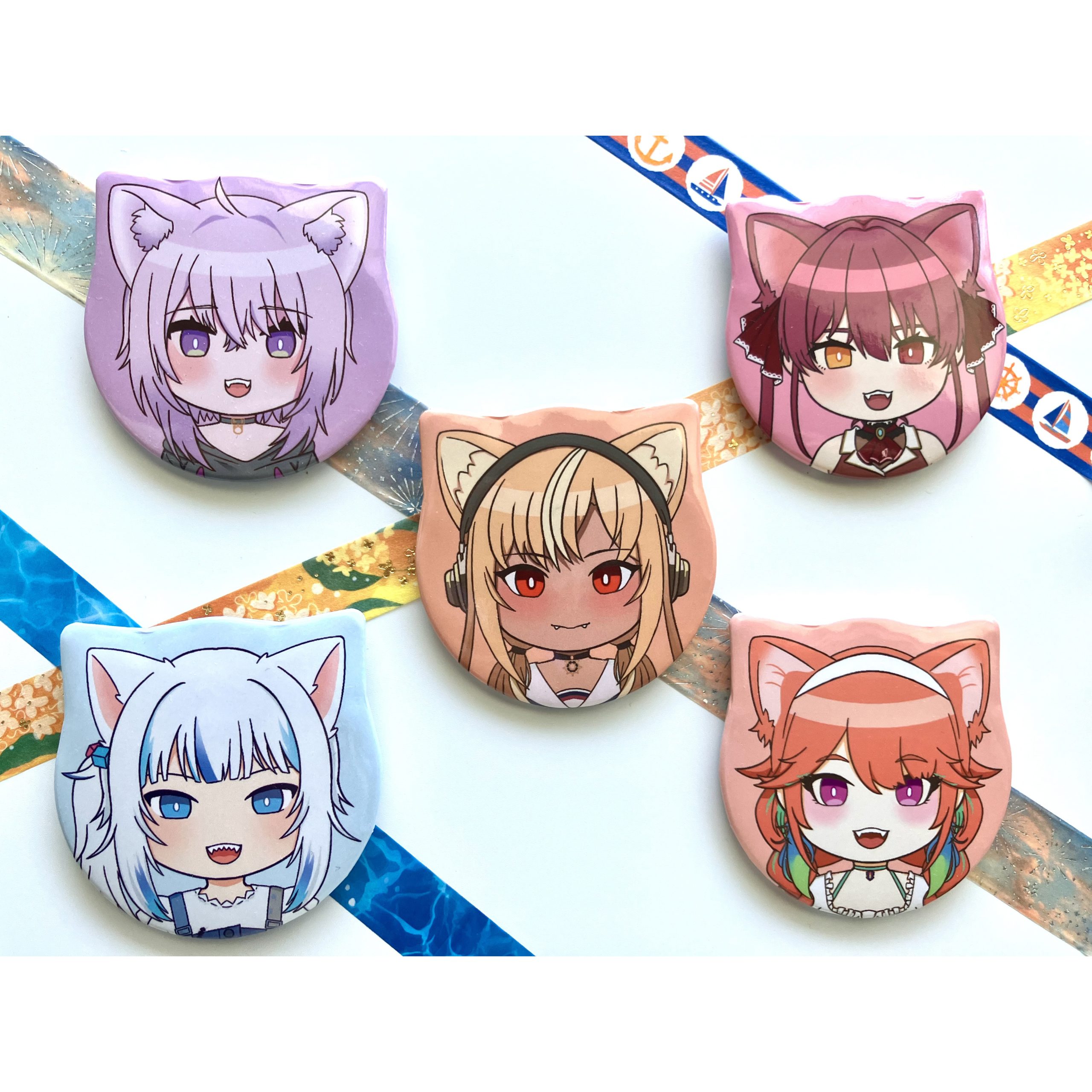 Five cat-eared anime character buttons in pastel colours, arranged on a white background with decorative washi tape.